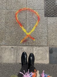 Low section of woman standing by orange and yellow drawing on footpath