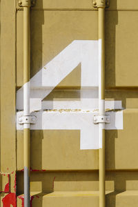 White silk-screen printing of number 4 on a mustard-colored shipping container