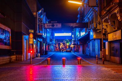 Illuminated street amidst buildings in city at night