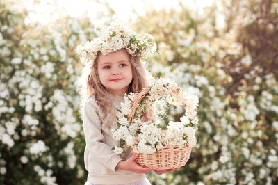 Portrait of cute girl holding flowers standing at park