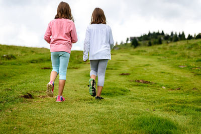 Rear view of women walking on grass