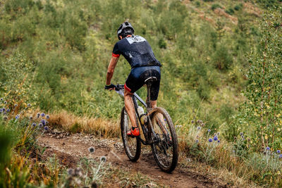 Dirty cyclist athlete biking mountain bike on trail. cross country cycling competition