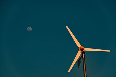 Low angle view of wind turbine against clear blue sky