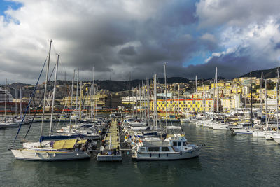 Sailboats in marina against cloudy sky
