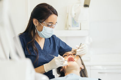 Female dentists examining woman teeth at hospital