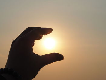 Silhouette hand against sky during sunset