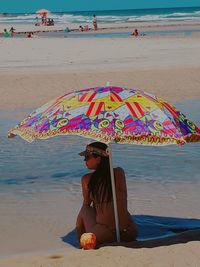 Woman sitting on beach against sea