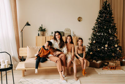 Family celebrates christmas holidays in winter at home. mom with teenage children in decorated room