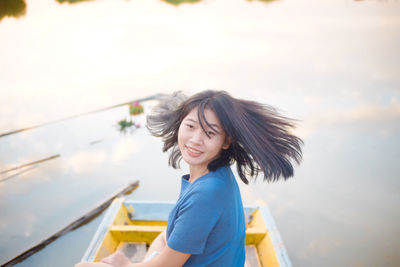 Portrait of smiling teenage girl sitting on boat in lake