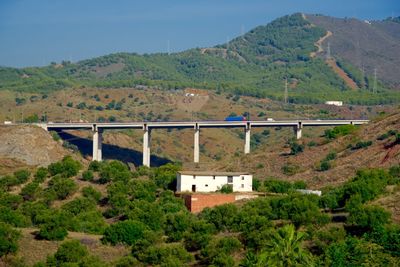 Bridge over mountain against sky