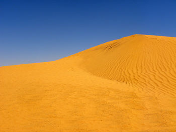 Scenic view of desert against clear blue sky