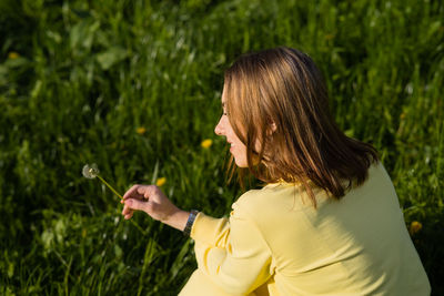 Side view of young woman with arms raised against plants