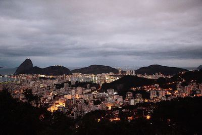 High angle view of illuminated cityscape against cloudy sky