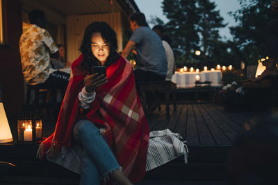 Woman sitting in illuminated park at night during winter