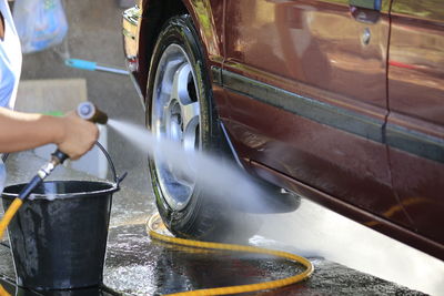 Cropped image of person washing car
