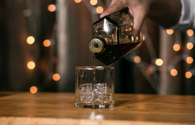 Close-up of hand pouring wine in glass on table