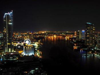 Illuminated buildings in city against sky at night