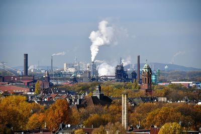 Smoke emitting from factory against sky