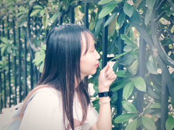 Midsection of woman with plants against trees