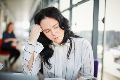 Close-up of stressed female student studying in university cafeteria