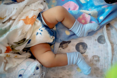 Low section of baby lying on bed at home