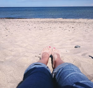 Low section of woman relaxing on sandy beach