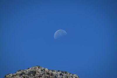 Low angle view of moon against clear blue sky