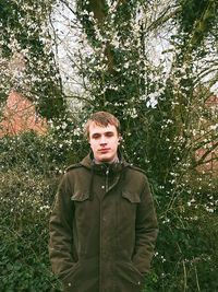 Portrait of young man standing against plants