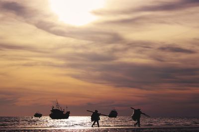 Silhouette people on beach against sky during sunset