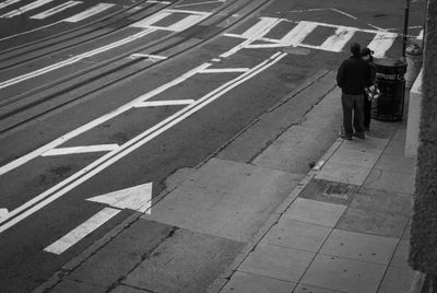 Rear view of man standing on road in city with right of way arrow