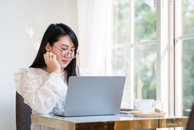 Young woman using phone while sitting on table