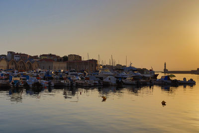 Boats moored in harbor at sunset