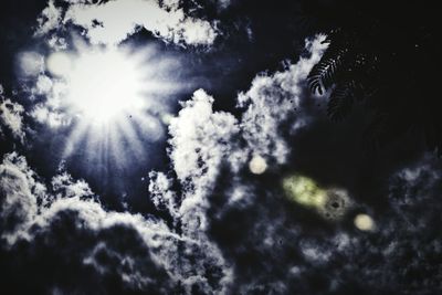 Low angle view of sun shining through clouds