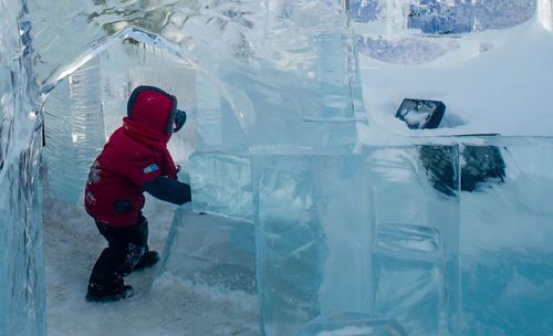 Side view of child playing in ice cave during winter