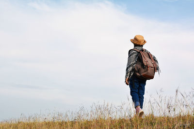 Girl walking on grassy field against sky