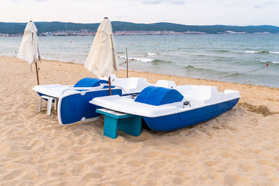 Deck chairs on beach against blue sky