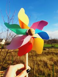 Close-up of woman holding pinwheel toy on field against sky
