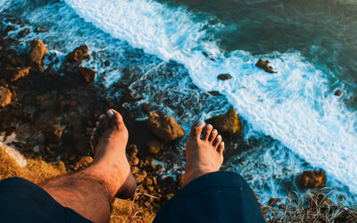 Low section of man on rocks by swimming pool