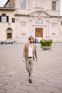 Full length portrait of young man against building in city