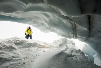 Low angle of mountaineer looking into a crevasse.