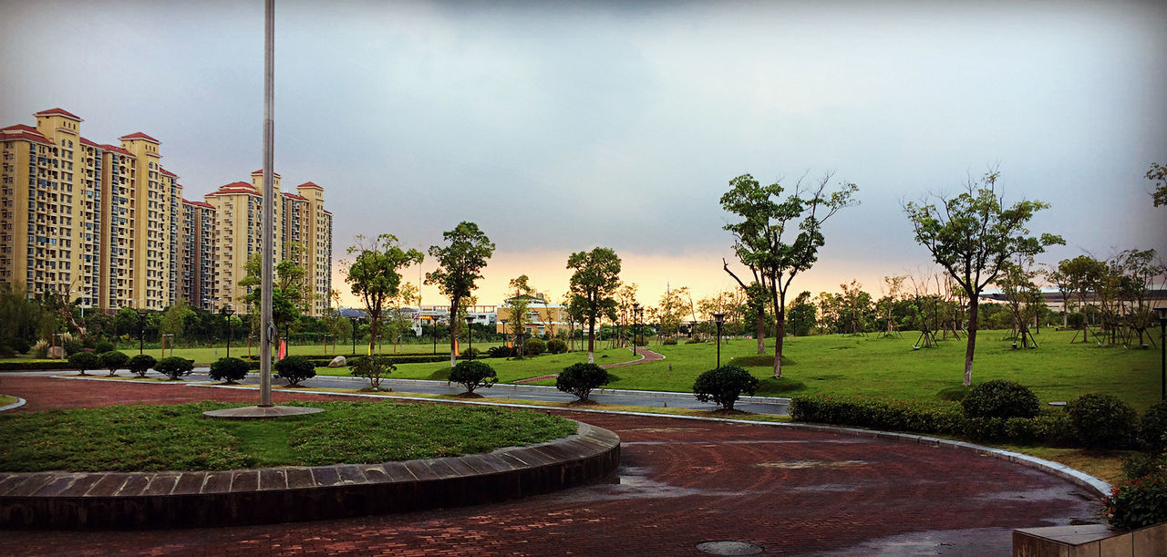 tree, sky, park - man made space, grass, built structure, architecture, cloud - sky, building exterior, footpath, park, incidental people, bench, lawn, green color, palm tree, growth, fountain, cloud, outdoors, nature