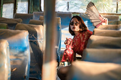 Portrait of smiling young woman sitting in abandoned bus