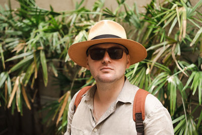 Portrait of young woman wearing hat standing amidst plants