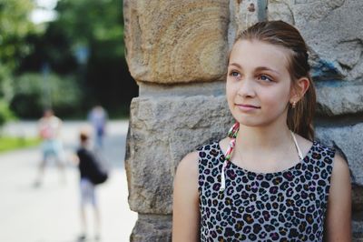 Smiling girl standing against wall