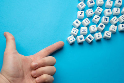 Cropped hand of person holding blister pack over blue background