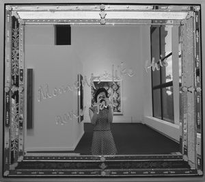Reflection of young woman on mirror with message in art museum