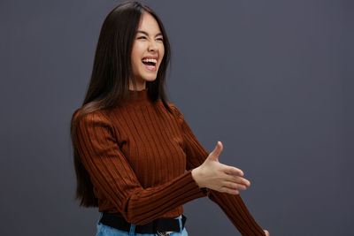 Portrait of young woman standing against black background