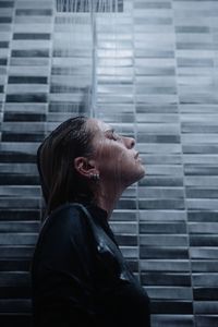 Woman taking a bath while standing in bathroom