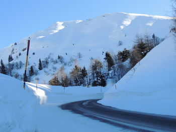 Snow covered road by mountain against sky