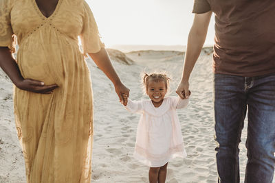 Young family of three walking and playing at beach